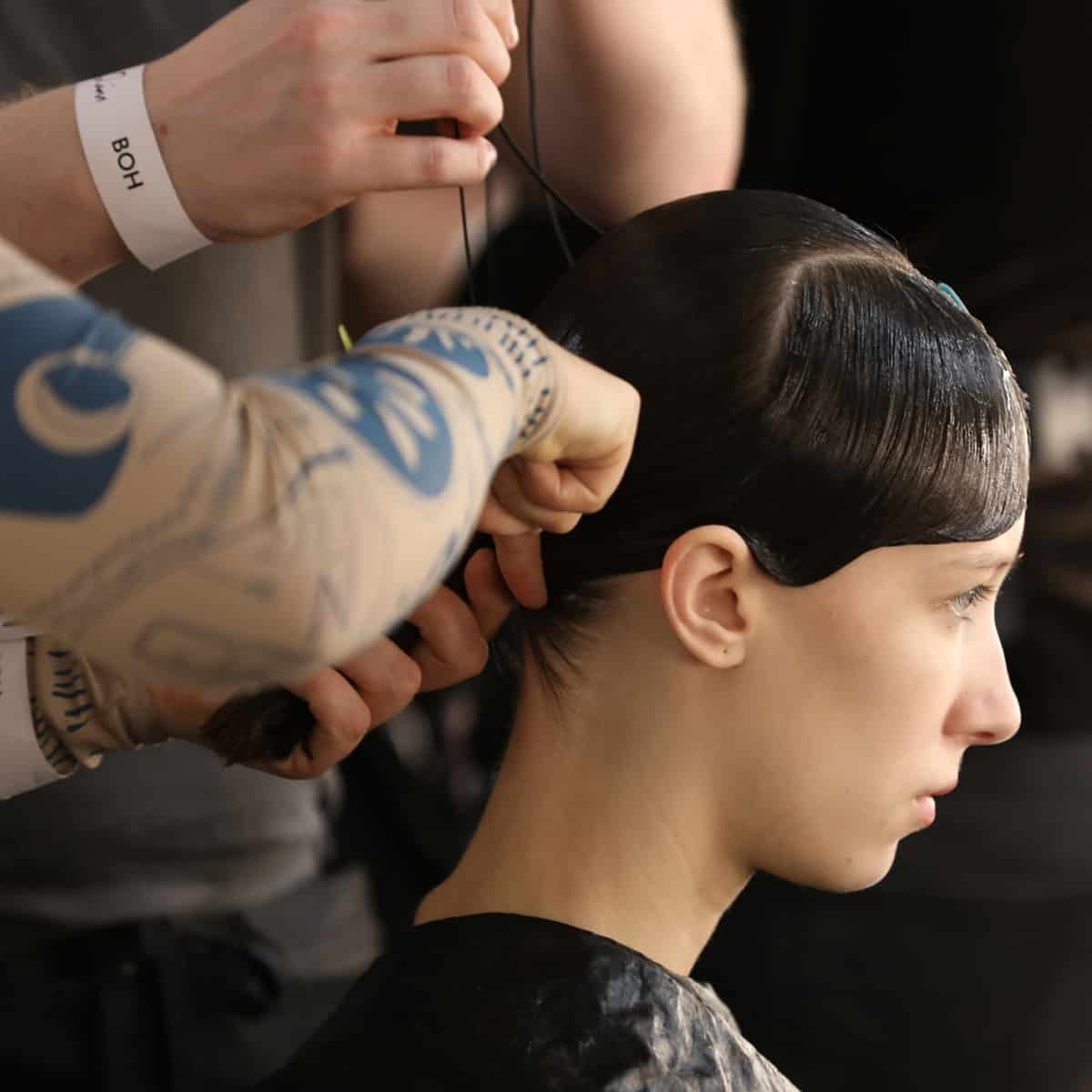 2 Stylists styling model's hair backstage at fashion week.
