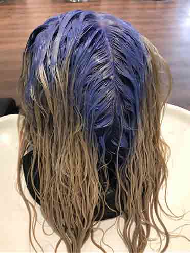 Woman in salon with purple bleach on roots