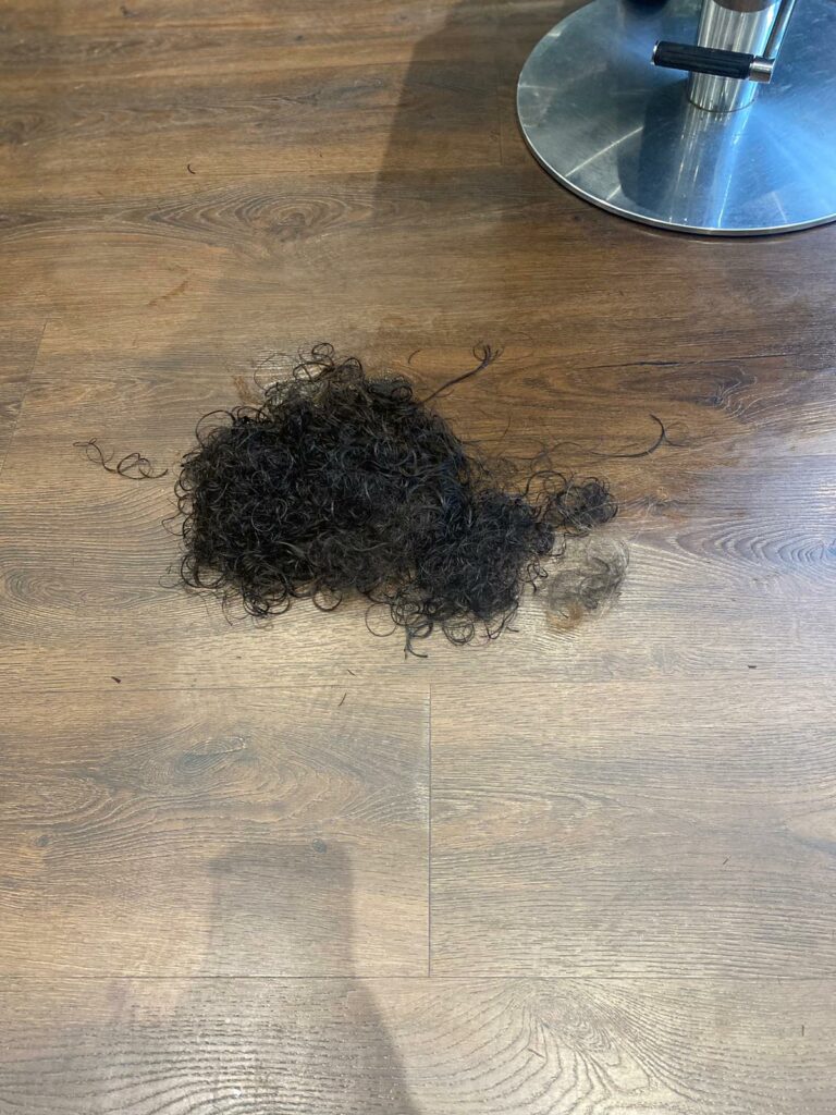 curly black hair cuttings on the floor