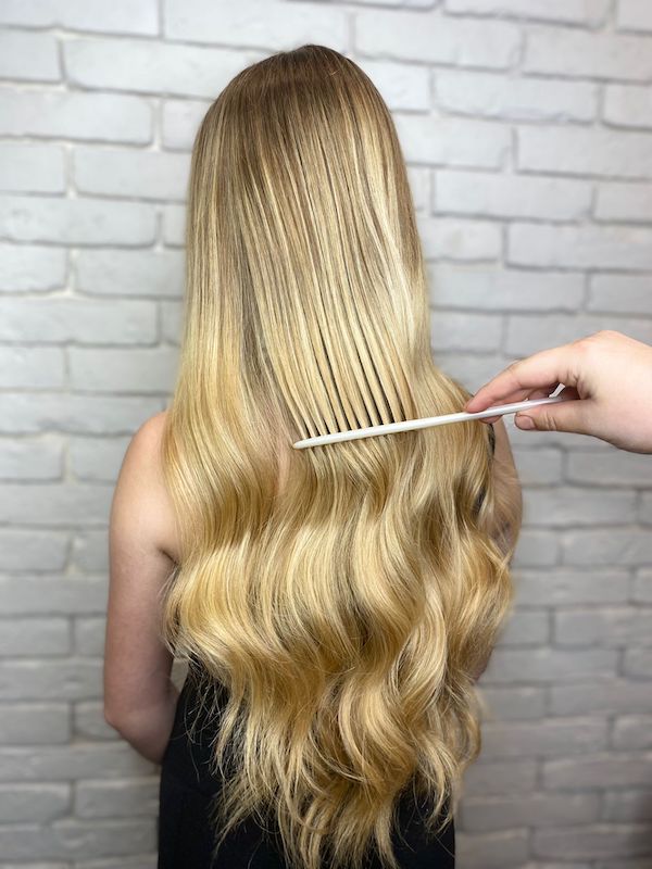 blonde balayage with hairstylist combing out curls